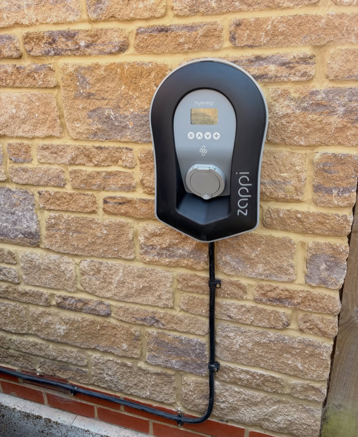 Myenergi Zappi EV charger on a sandstone wall