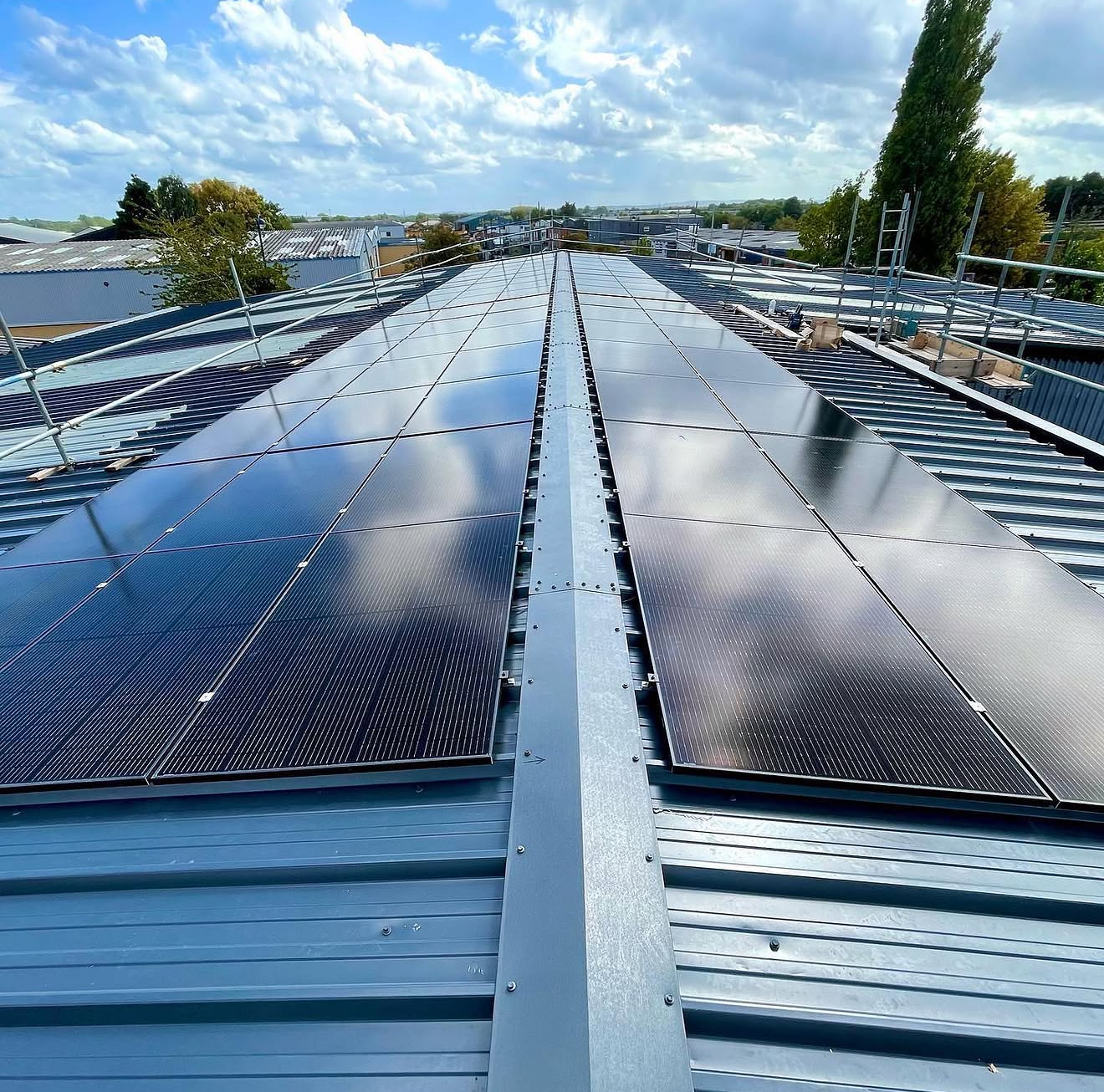 Two long rows of black solar panels on a pitched metal commercial roof